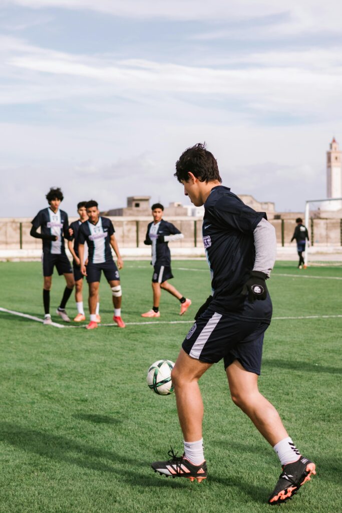 Group of teenage soccer players practicing on an outdoor field on a sunny day.