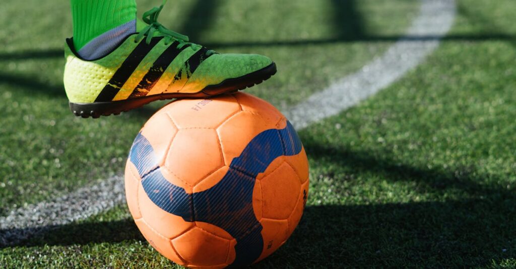 Dynamic shot of a soccer player's foot on a vivid orange ball on a lush green field.