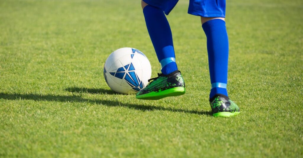 Close-up of a soccer player dribbling a ball on a vibrant green field in Portugal.