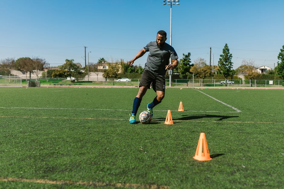Athletic man practicing soccer drills with soccer training cones on a soccer field.